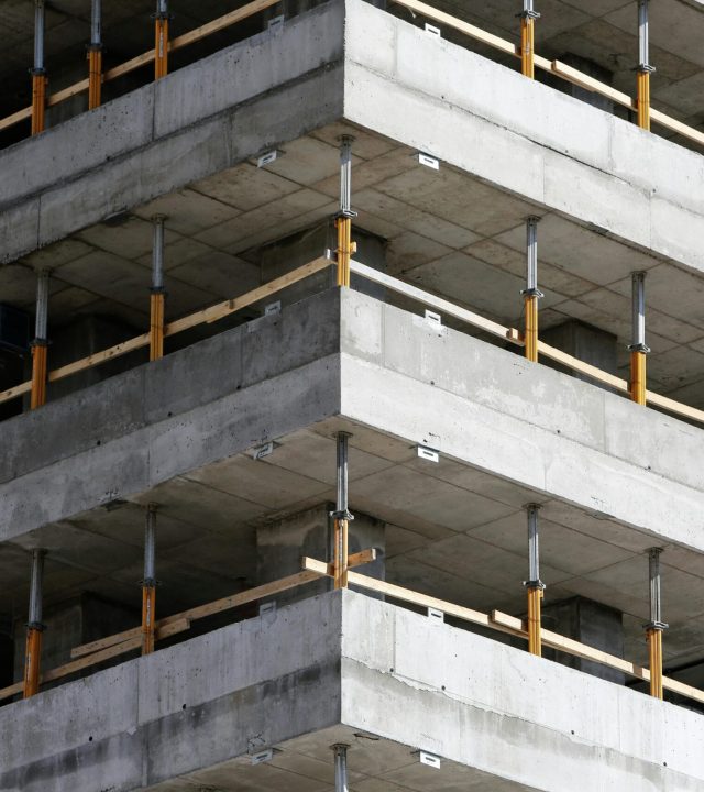 Close-up of an unfinished multi-level concrete building with steel reinforcements.